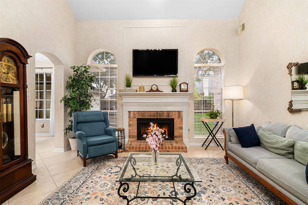High vaulted ceilings and a cozy fireplace flanked by graceful windows emphasize the charm and warmth of the family room.