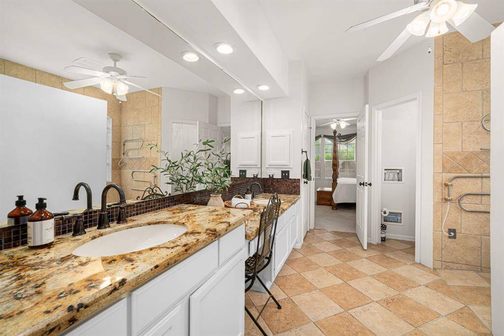 This grand primary bathroom features gorgeous granite countertop with dual sinks, a vanity space, and HEATED tile floors!