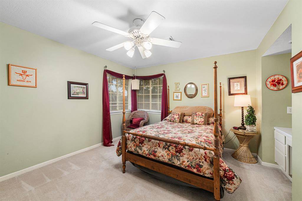 The roomy secondary bedroom features a built-in desk nook, ceiling fan and a large corner window.