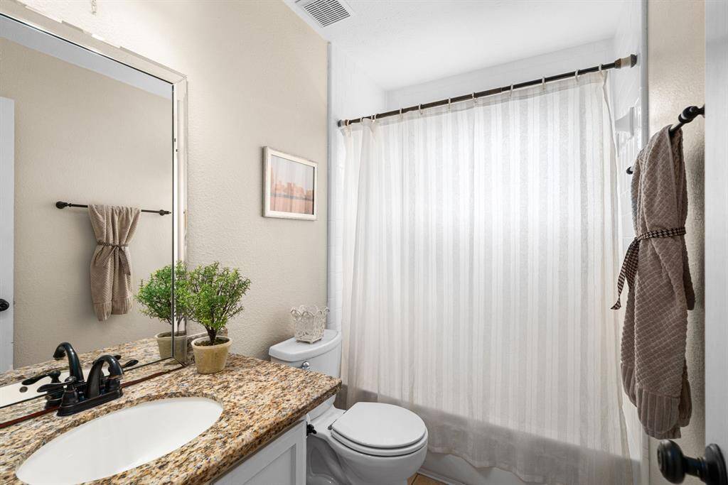 Full bathroom with granite counter, beautifully framed mirror, and tub/shower combo just off of second bedroom.