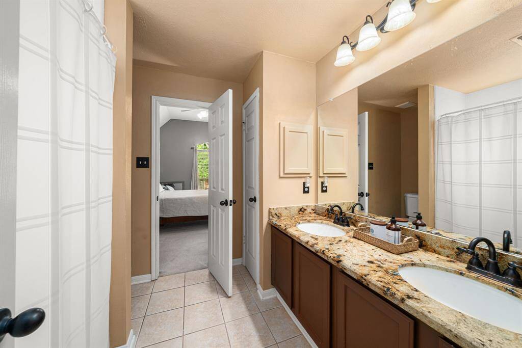 Connecting bathroom between 3rd and 4th bedrooms with granite countertops, dual sinks, decorative lighting , and tub/shower combo.