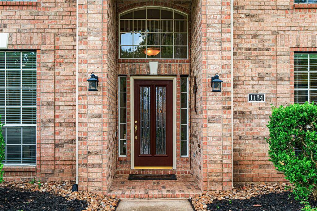 Step up to the elegant entrance featuring a lovely wood front door with decorative glass panels, and sconces that light up at dusk.