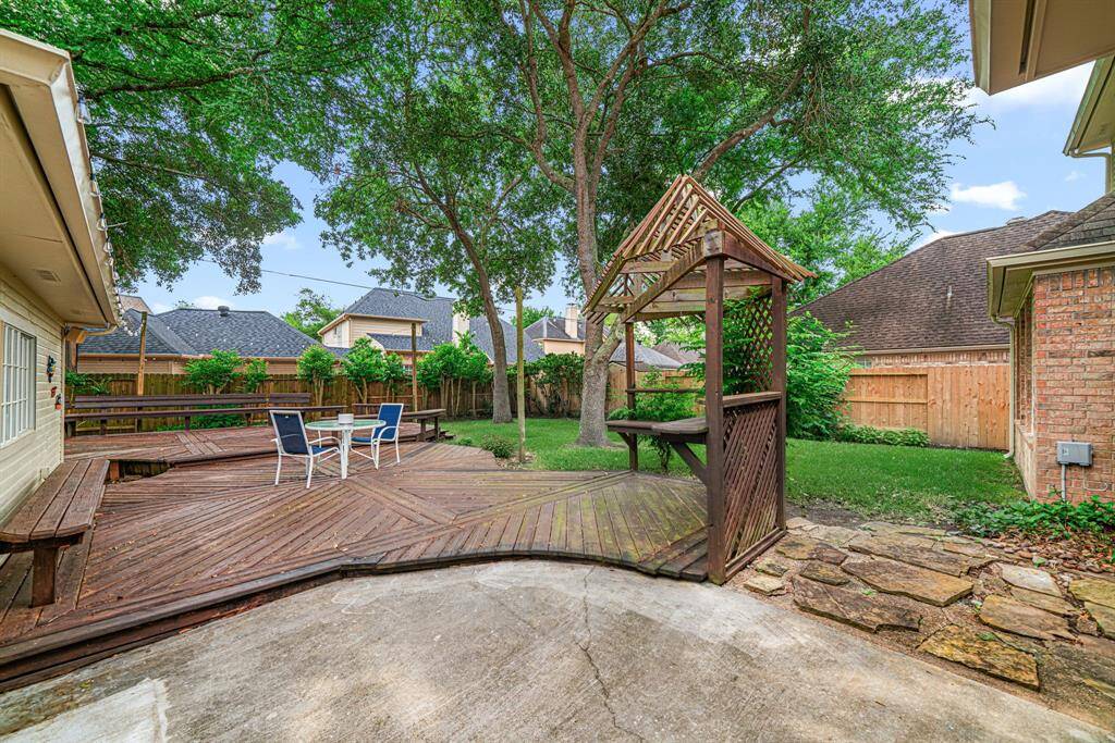 Your own backyard park featuring a spacious wooden deck, surrounded by mature trees and greenery.