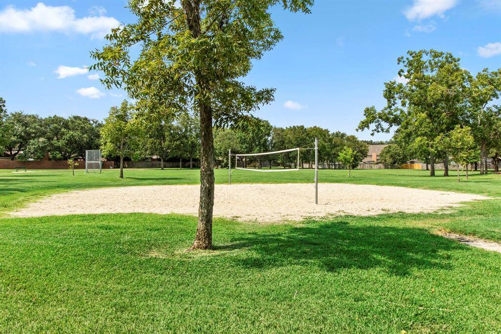 The sand volleyball court and grassy park surrounded by trees, provides a fantastic gathering spot for outdoor recreation.