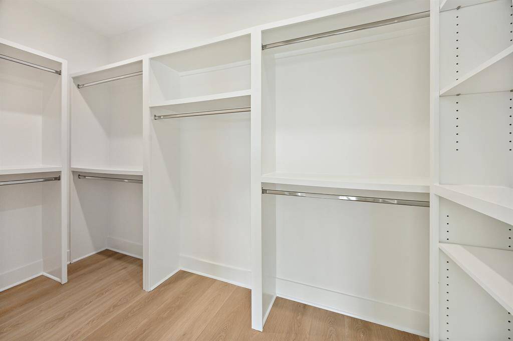 Primary closet with shelves for storage and hanging rods. You will not worry about storage in this home!