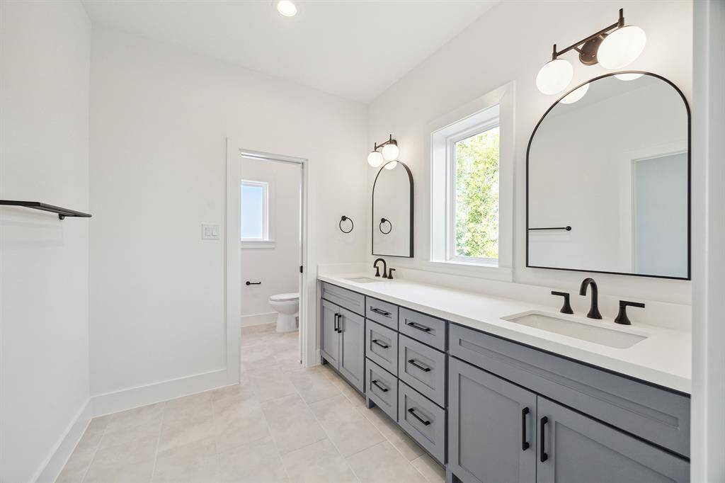 Jack and Jill full bath accessible from both bedrooms with tub/shower combination, classic tiles, dual vanities, decorative fixtures and large casement window inviting natural light