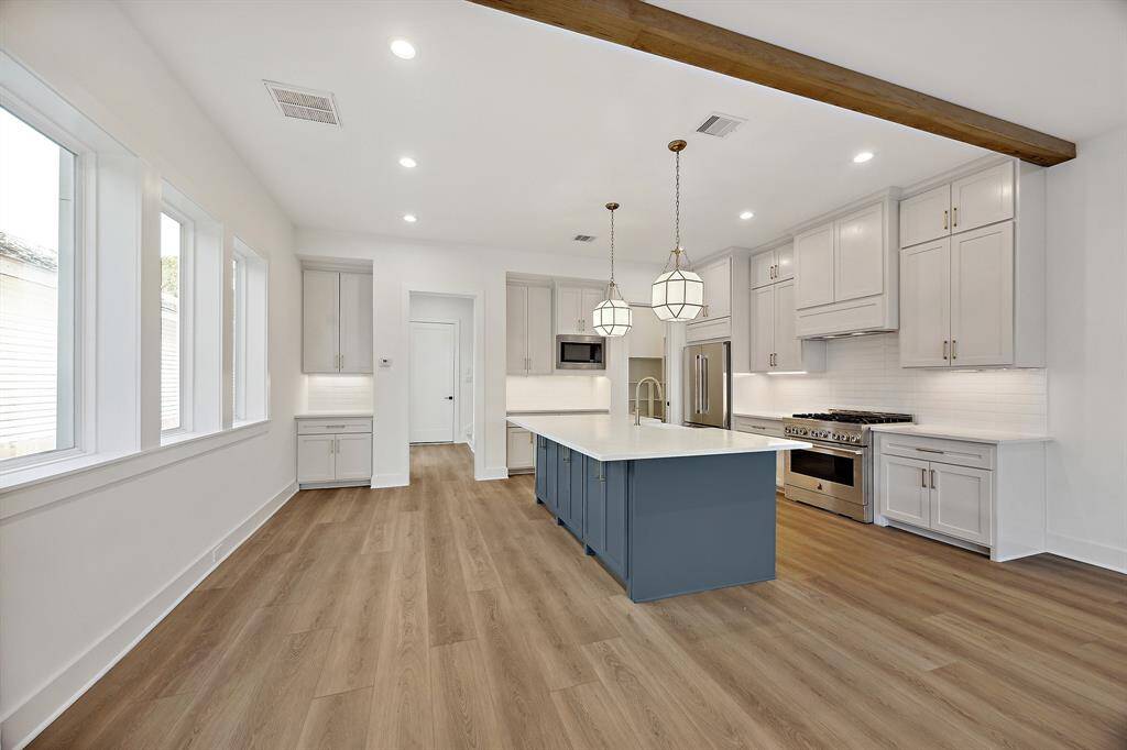 Well appointed kitchen with modern flair featuring stainless steel appliances and framed vent-a hood. Bar overhang allows for stools to rest under the counter. Pictured in the kitchen is a walk-in pantry with space saving pocket door. This Chefs kitchen features soft close drawers and cabinets allowing to close silently and smoothly