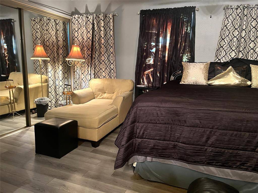 Spacious upstairs primary bedroom with laminate flooring & mirror-accented closet doors