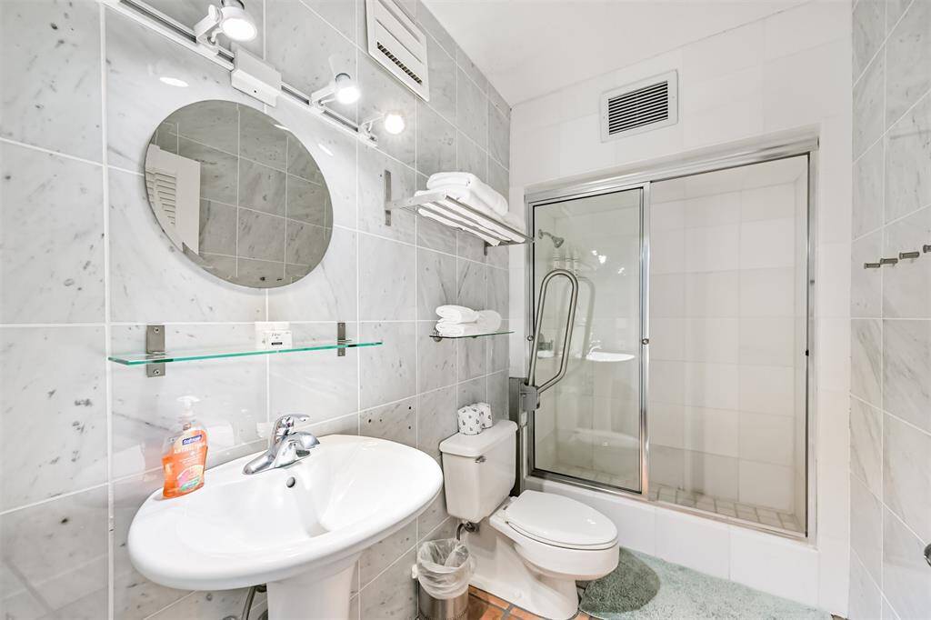 Modern bathroom with floor to ceiling tile and nice light fixtures.