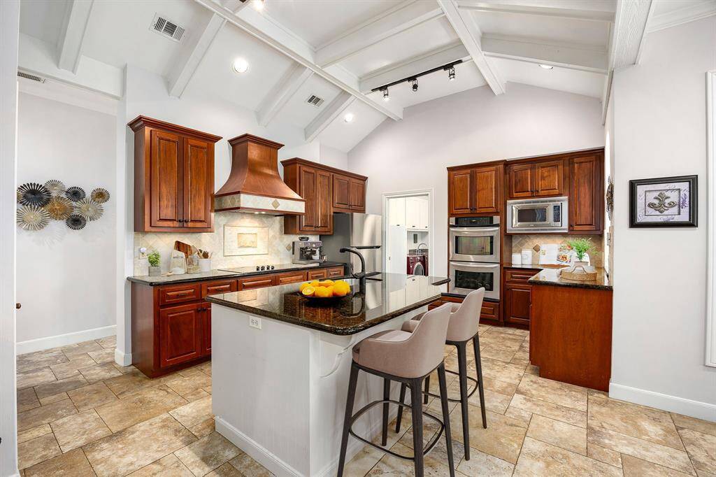 This stunning kitchen displays such a beautiful contrast with the dark stained cabinets, custom neutral paint, granite countertops, light modern backsplash, and SS appliances, oversized kitchen island with extra storage, breakfast bar, recessed lighting, high ceilings and walk in pantry. *Virtually Staged