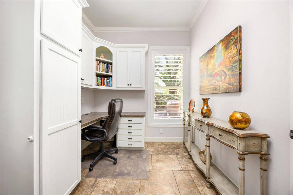 The mud room doubles as a utility room and office, with a built-in desk, high ceilings, large tile flooring, and a window with plenty of natural light.