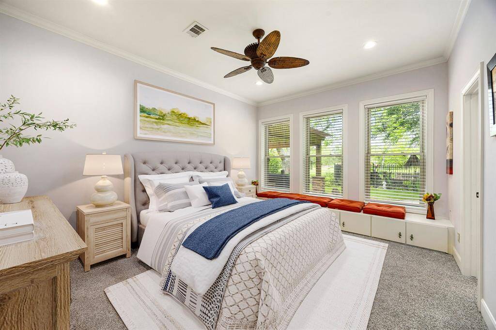 Secondary bedroom features plush carpet, custom paint, dark stained ceiling fan with lighting and a large window with privacy blinds. *Virtually Staged