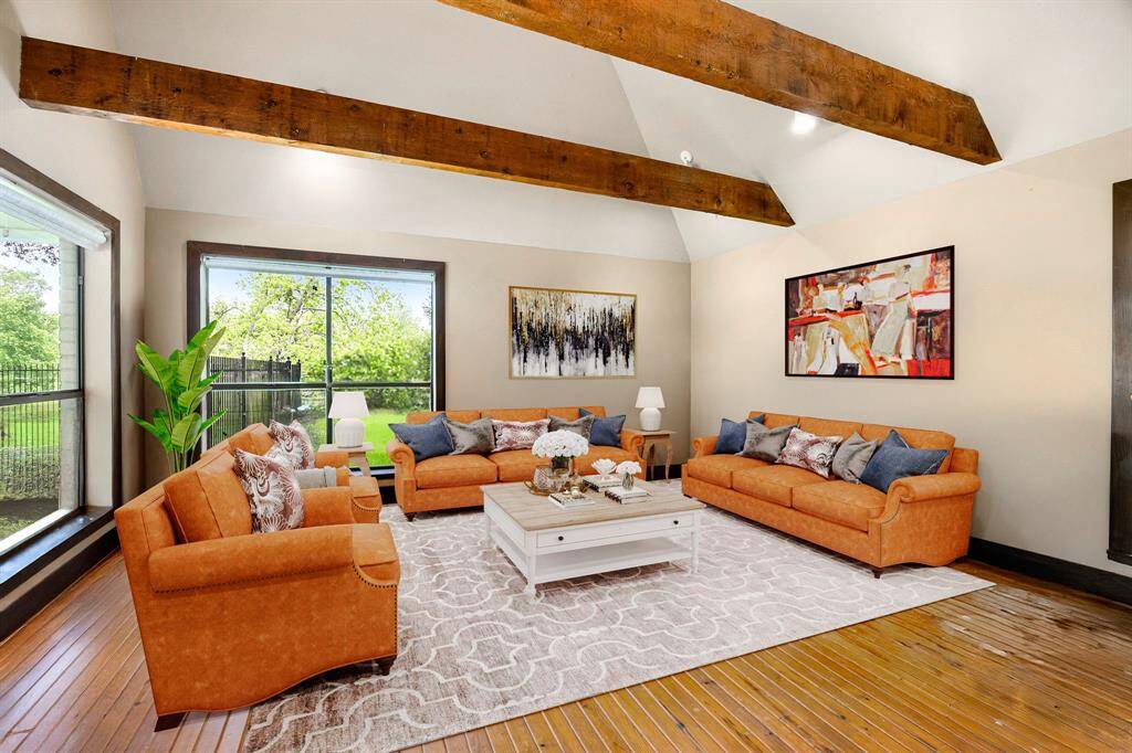 Step into the cozy charm of this guest house living room, where large windows flood the space with natural light, highlighting the warm wood floors and rustic wood-beamed ceiling. A perfect blend of comfort and character, ideal for relaxing or entertaining. *Virtually Staged