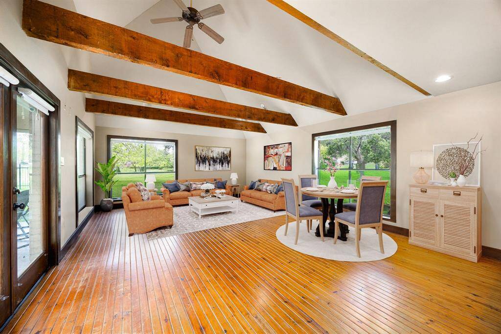 This sun-drenched guest house living room offers a perfect balance of rustic charm and comfort. With its rich wood floors, exposed beams, and oversized windows, it creates a cozy yet open atmosphere your guests will love. *Virtually Staged