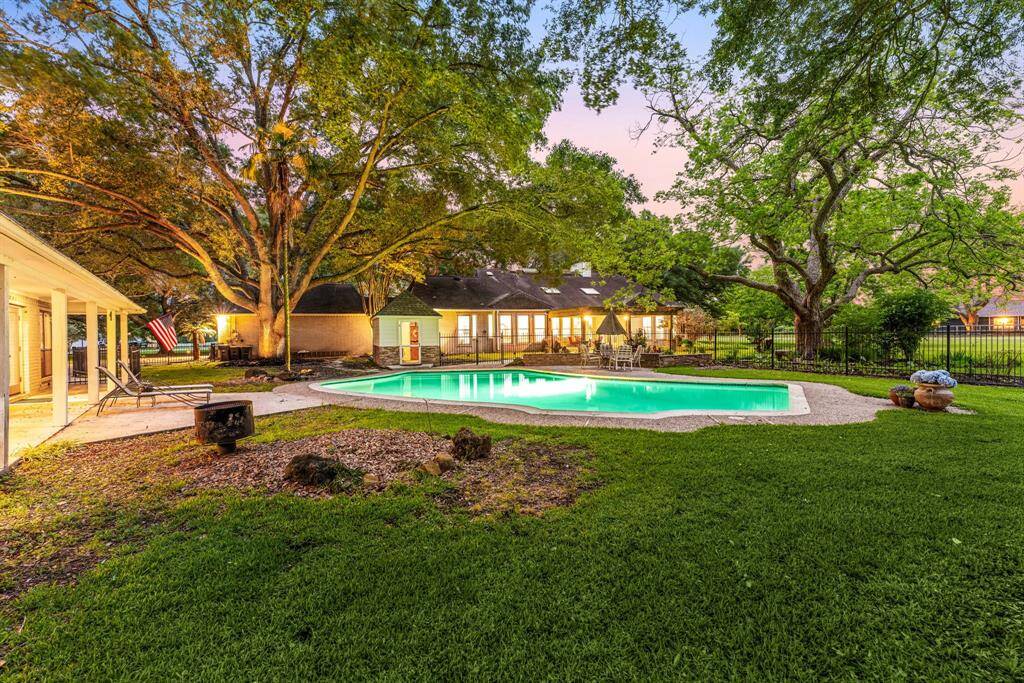 Surrounded by mature oak trees and vibrant greenery, this serene backyard offers a luxurious pool and ample space to lounge, entertain, or unwind in total privacy. Resort-style living right at home.