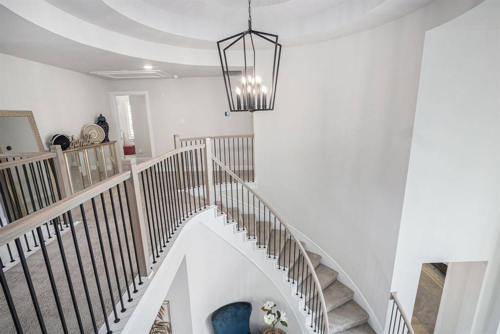 Beautiful staircaise, chandelier, and recessed ceiling.