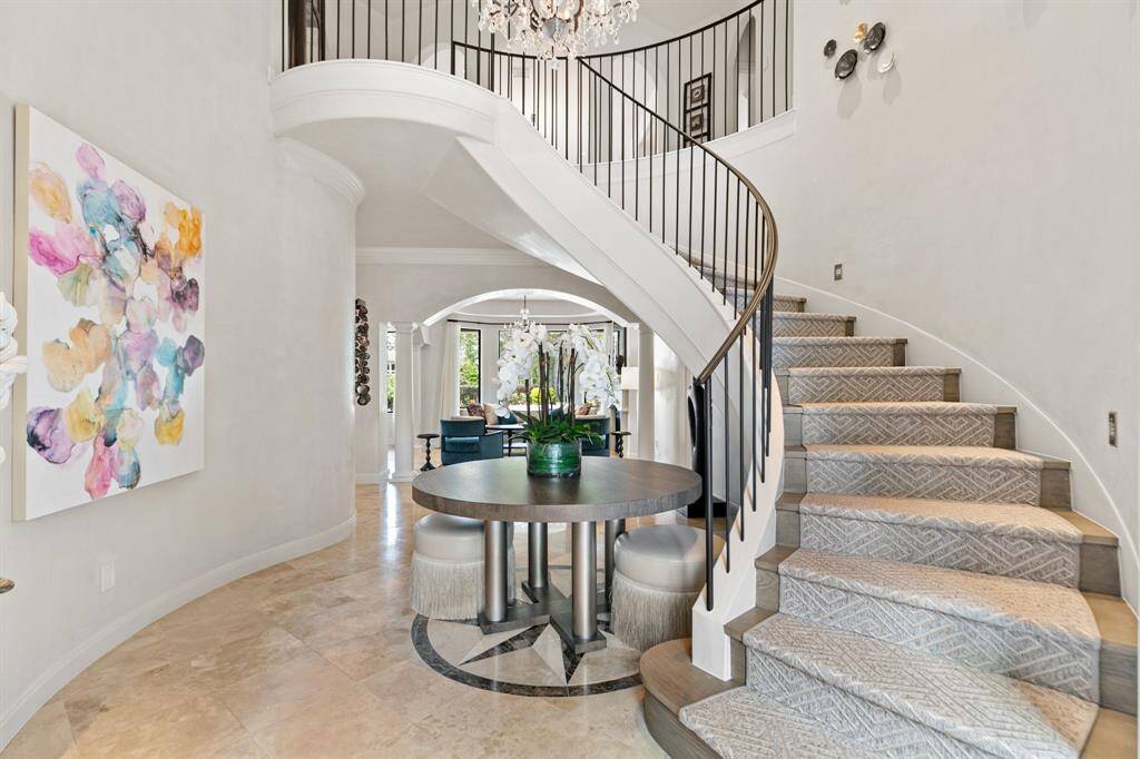 This exquisite entryway features plaster walls and a sweeping wood staircase with a custom carpet runner and wrought-iron handrail.