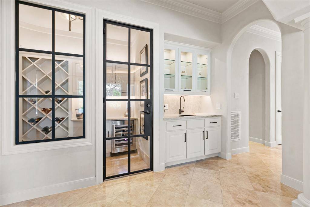 The wine room includes a steel door, KitchenAid wine refrigerator, a contemporary light fixture and plenty of wine storage.