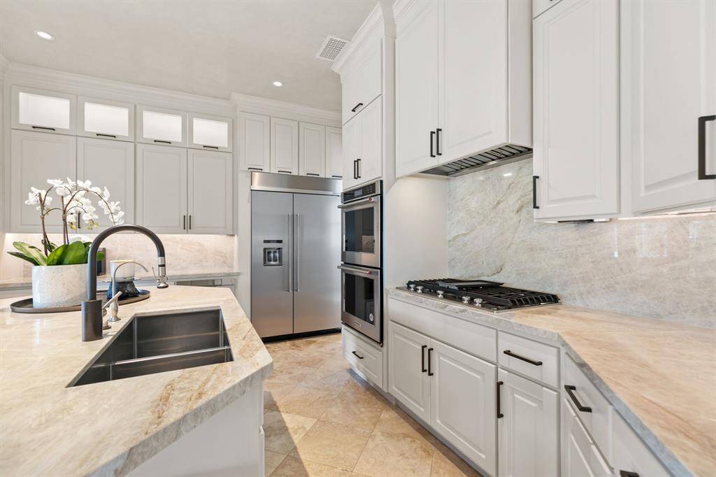 Notice the under-cabinet lighting, deep sink and stunning Taj Mahal Quartzite counters and backsplash.