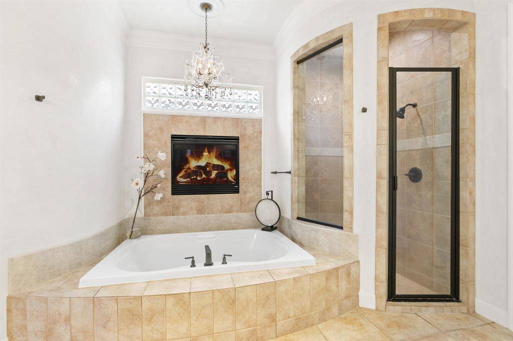 Enjoy this spa-like bath with the soaking tub, separate shower, fireplace and crystal chandelier.