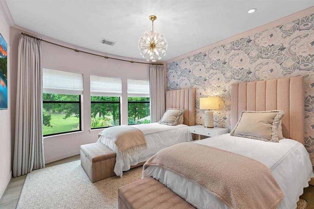 Bedroom 2 is so pretty in pink and features shades, custom drapes, wall covering and a darling chandelier.