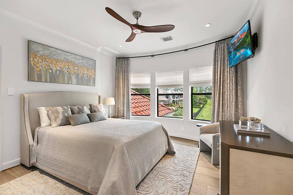 Bedroom 4 features shades, custom drapes, a contemporary ceiling fan and an ensuite bath.