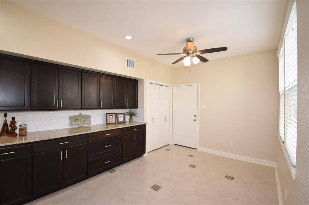 Breakfast room highlighted by tile floors, service bar, pantry, ceiling fan with light fixture and a door to the two car garage.