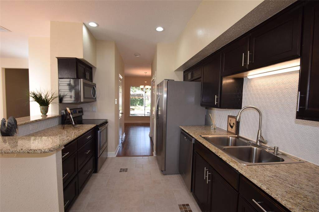 Kitchen offering tile floors, tile back splash, granite counter tops, electric cooking, flat surface cook top, built-in microwave, refrigerator and opens to the dining room, family room and breakfast room.