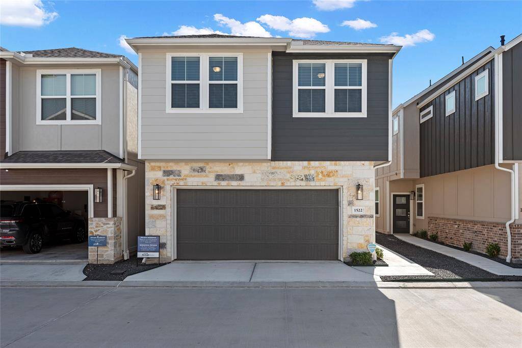 Modern two-story townhome featuring a sleek exterior made up of stone and siding. Double car garage.