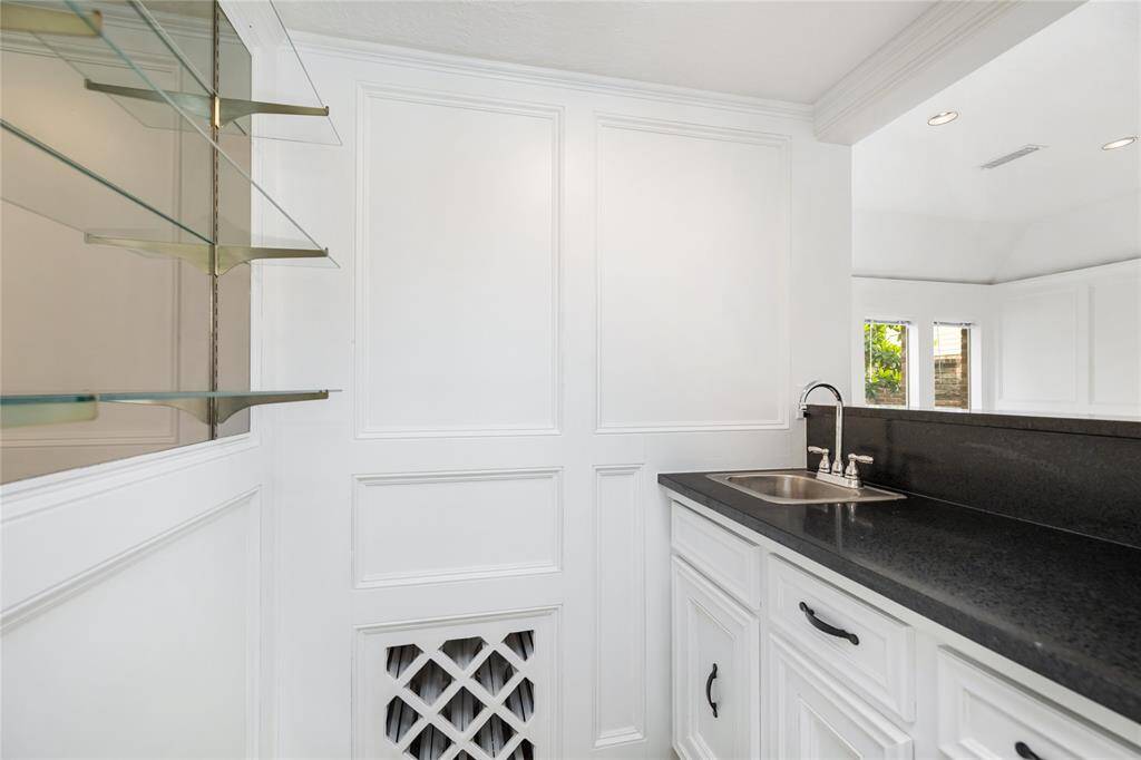 The wet bar is a functional and stylish feature, complete with a sink, wine rack, and ample shelving for your favorite bottles and glassware. Thoughtful storage ensures everything has its place, while the convenient service window to the living room allows for easy serving during gatherings, making it an ideal spot for entertaining.
