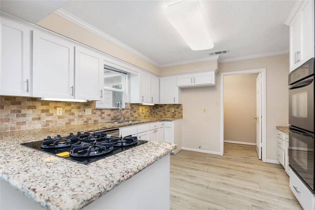 This chef’s kitchen features granite countertops, an upgraded backsplash, and expansive cabinetry with under-cabinet lighting. Double ovens, a gas cooktop, and pots and pans drawers ensure convenience and functionality for cooking and entertaining.