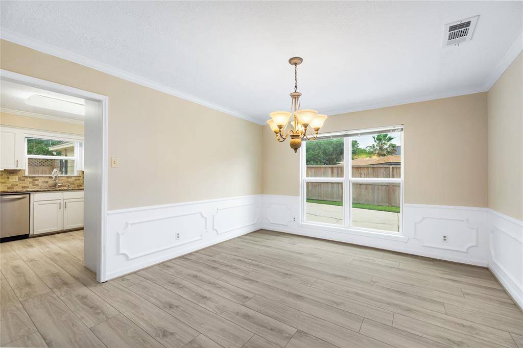 The formal dining room features beautiful wainscoting details and is illuminated by an elegant light fixture, creating a refined atmosphere. Located just off the kitchen, this space is flooded with natural light, making it perfect for both intimate dinners and lively gatherings.