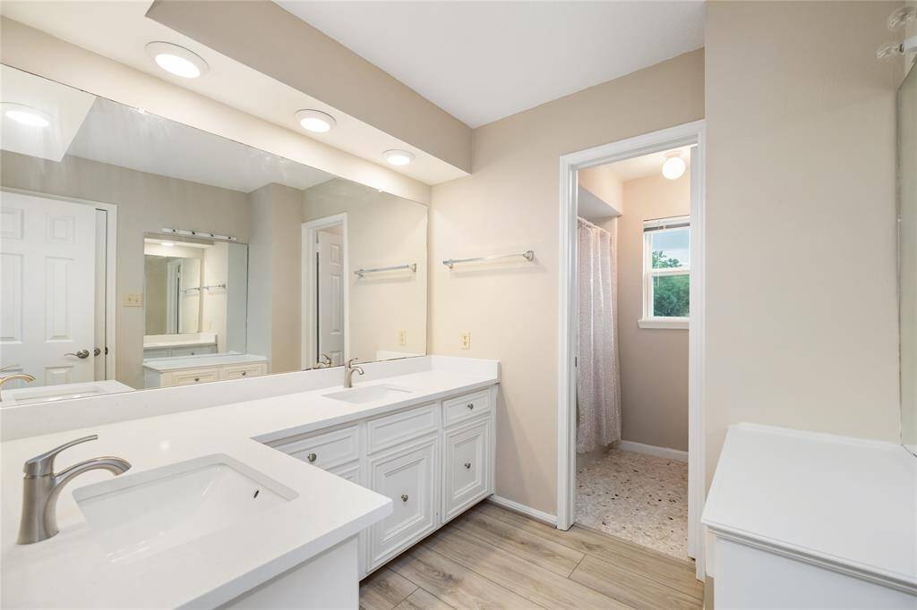 This full bathroom features dual sinks and plenty of cabinet space for storage. The tub/shower combo and separate vanity area provide added convenience and functionality, making it a perfect space for everyday use.