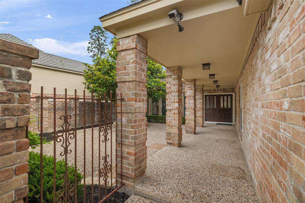 A unique and inviting feature of this home is the long, covered walkway leading from the driveway to the grand double-door entry. As you follow the pebbled concrete path past stately columns and the expansive front patio, you're greeted with a sense of arrival that’s both elegant and welcoming.