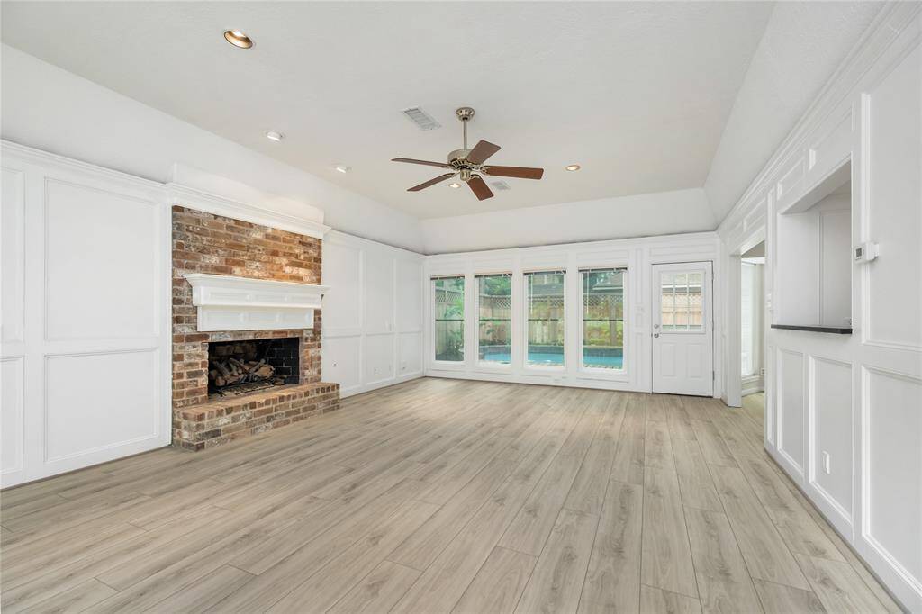 The spacious living room features a cozy wood-burning fireplace, offering a warm and inviting atmosphere as it overlooks the stunning backyard oasis. With the wet bar conveniently within reach, this space is perfect for both relaxing and entertaining.