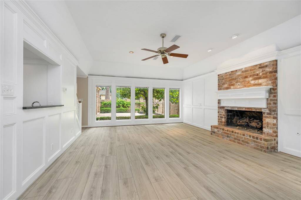 The living room’s stunning board and batten walls, combined with a beautiful wooden mantle on the brick fireplace, create a warm, inviting atmosphere. The tray ceiling adds an extra touch of elegance, enhancing the room’s sense of space.
