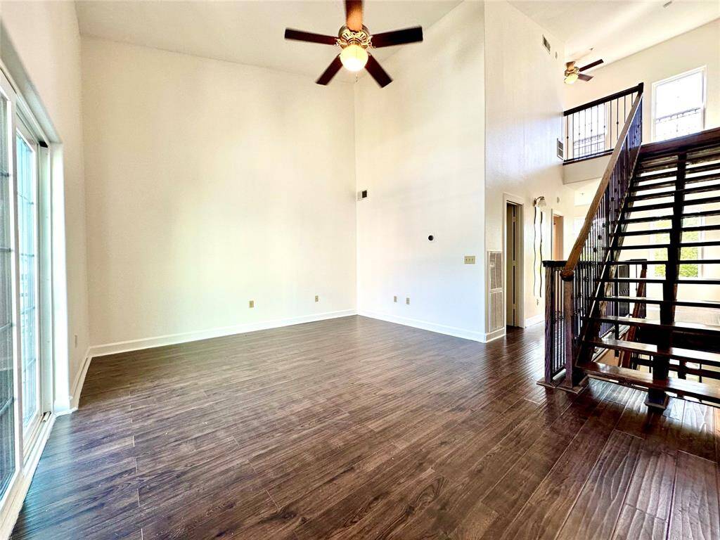 Primary bedroom with high ceiling, ceiling fan, large windows, beautiful floors, and lots of natural light.