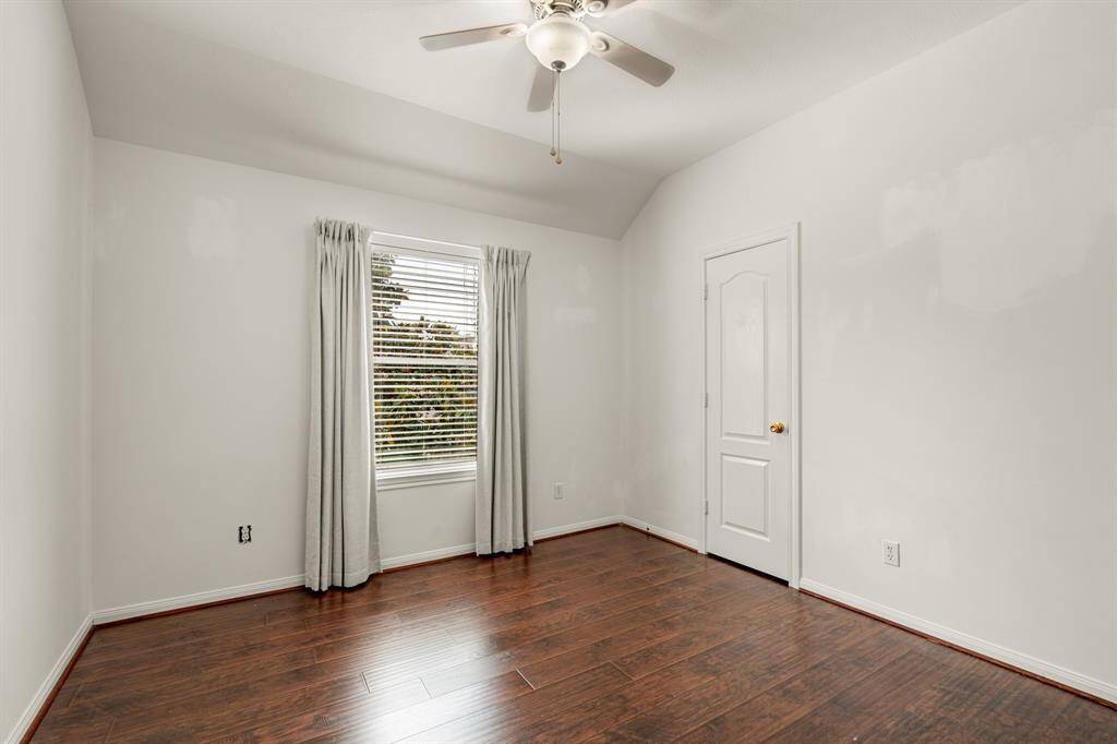 Another spacious secondary bedroom featuring bright natural light, ceiling fan, wood floors, and curtains!