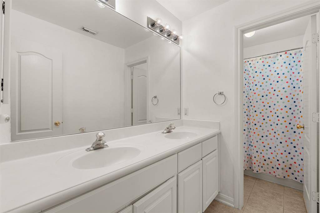 Located just off the secondary bedrooms, this full bathroom offers additional privacy with separated vanity area and shower making it easy to share and get ready. It features with white cabinets, a spacious tub and shower, dual sinks, and large mirror.