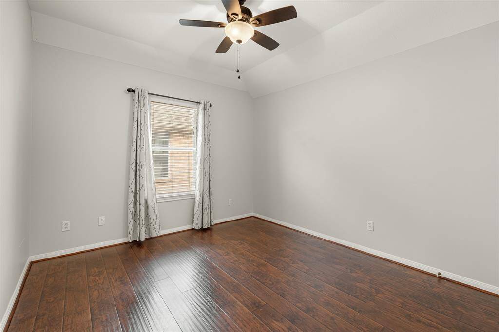 The final of the secondary bedrooms with wood floors, a ceiling fan, natural light, and spacious closet.