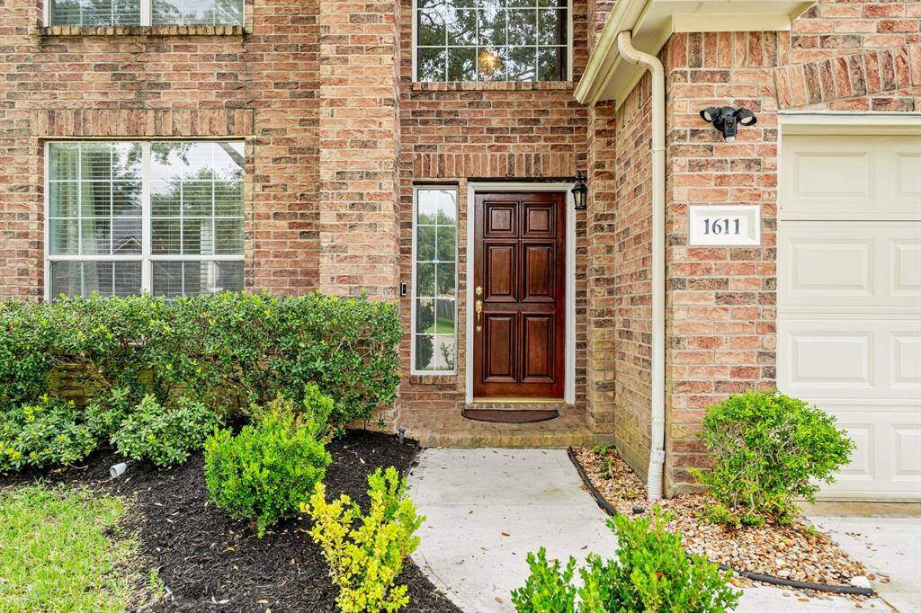 As you approach the home, you're greeted by a warm brick, a spacious front porch, stained wood front door, and iron porch light.