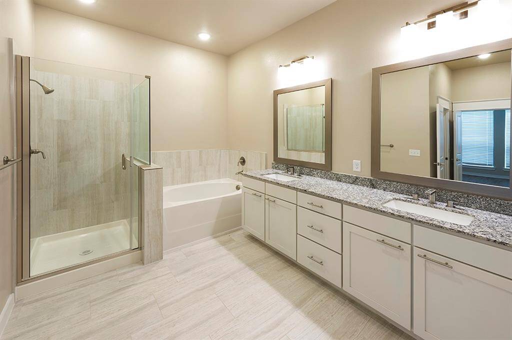 Primary bath with custom framed mirrors, double sinks, and separate tub and shower
