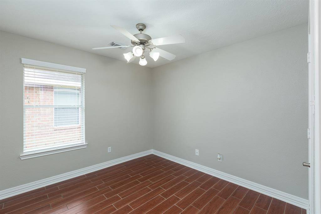 Secondary bedroom # 1 with wood-looking tiles and ceiling fan