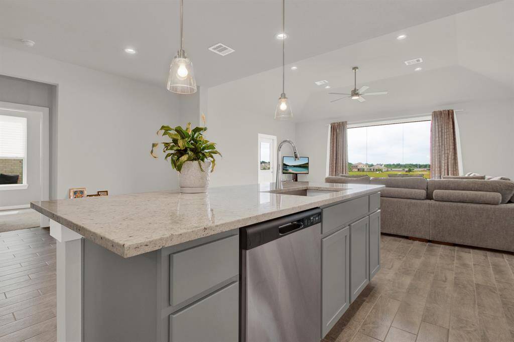 This modern home features an open-concept living area with a spacious kitchen island, pendant lighting, and a cozy living room. Large windows provide abundant natural light and scenic views, creating an inviting and airy atmosphere.