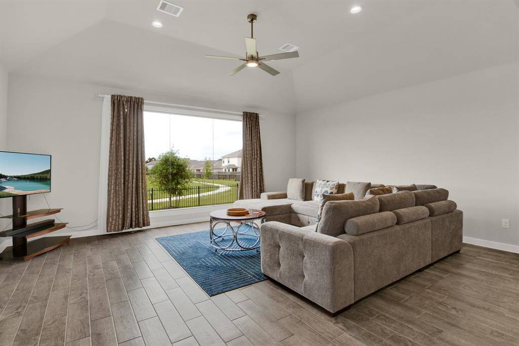 Bright living room with large windows offering a scenic view of a pond and fountain. Ideal for relaxation and enjoying the outdoors from inside.