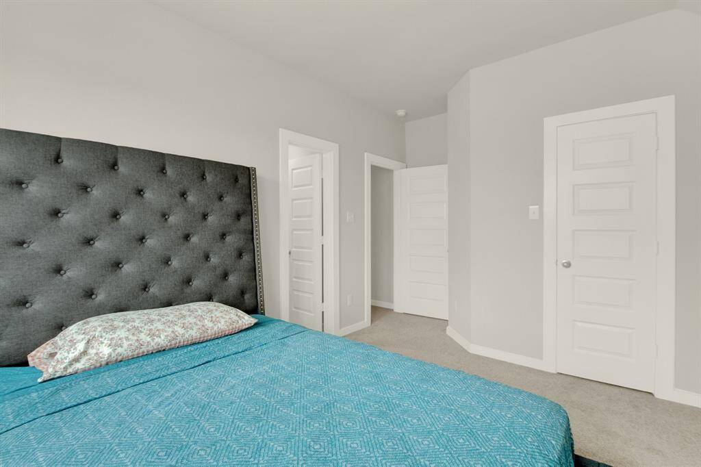 Cozy bedroom with a soft gray color palette. Ample natural light and multiple doors provide functional access and storage.