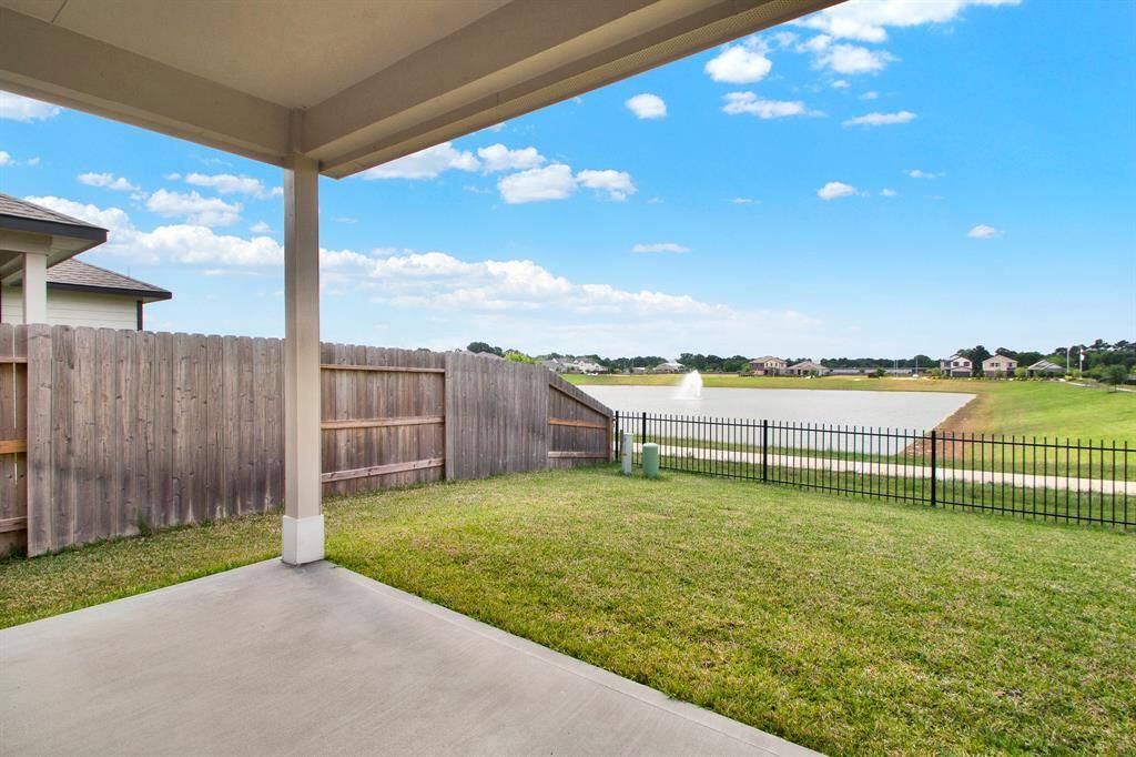 Covered patio overlooking a fenced backyard with a view of a pond and fountain. Perfect for relaxation and outdoor enjoyment.