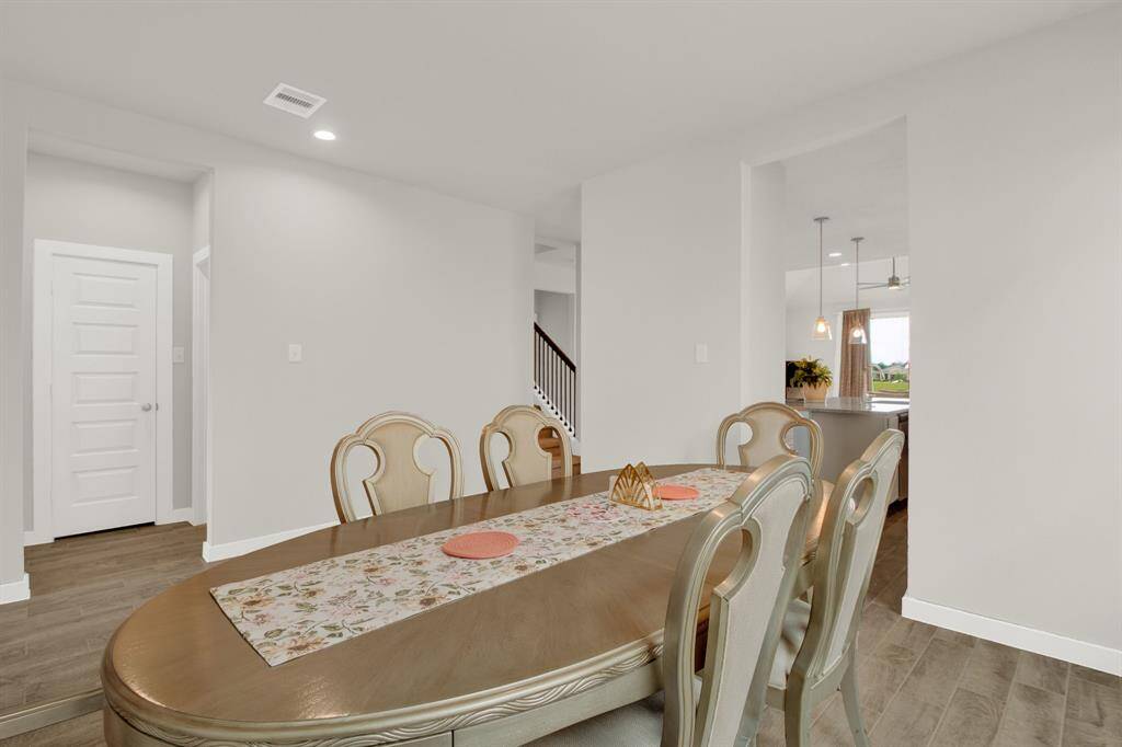 Bright dining area featuring large windows that bring in natural light. The space connects to the kitchen with gray cabinets and an open living area, creating a seamless flow ideal for entertaining.