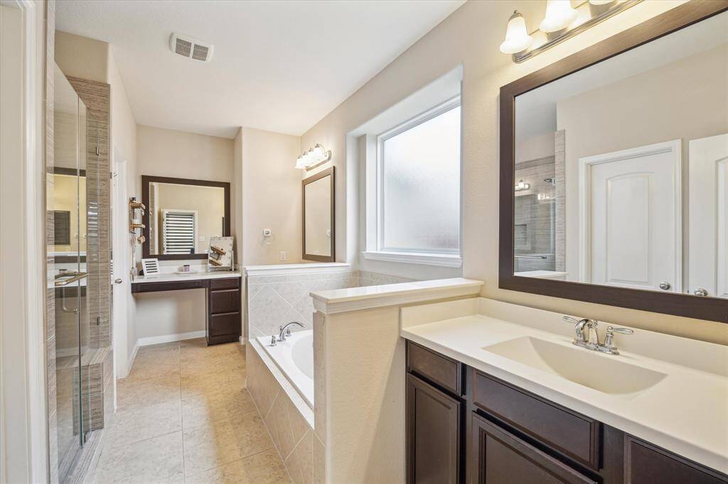 Luxurious primary en-suite bathroom featuring double sinks, a relaxing soaking tub, and a spacious walk-in shower.