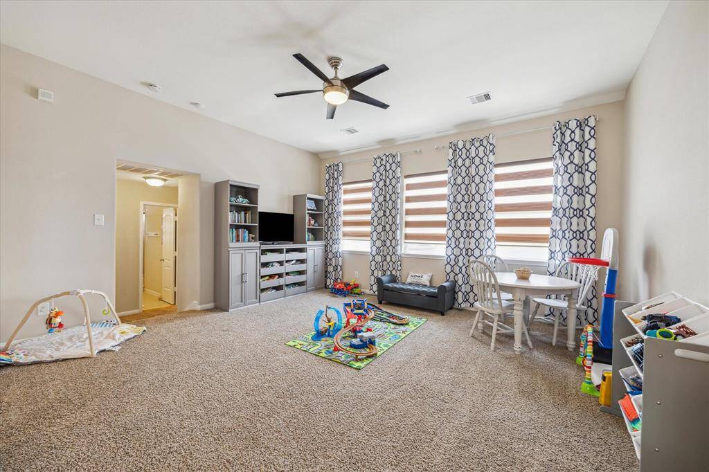 Spacious game room with large windows offering beautiful views of the backyard.